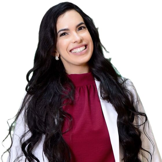 Bárbara Carvalho sorrindo, de jaleco branco